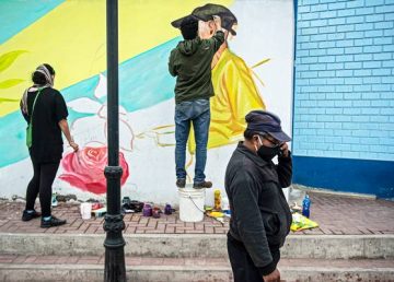 El muralista de 35 años Daniel Manrique, quien de forma gratuita se dedica a pintar los retratos de víctimas de COVID-19 frente a una pequeña plaza de su vecindario, en el cerro de San Cristóbal de la capital peruana. Fotografía: AFP