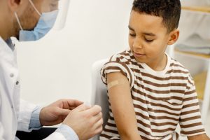 Male doctor stick a band-aid to a boy after a vaccination