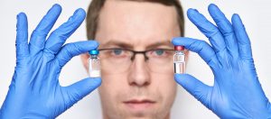 Male person in blue glove hold vaccine bottles. Injection drug pharmacy concept. Medical nurse therapy. People hand health science. Horizontal banner. Man face