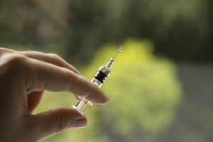 Closeup shot of a female holding a syringe, on a blurred background